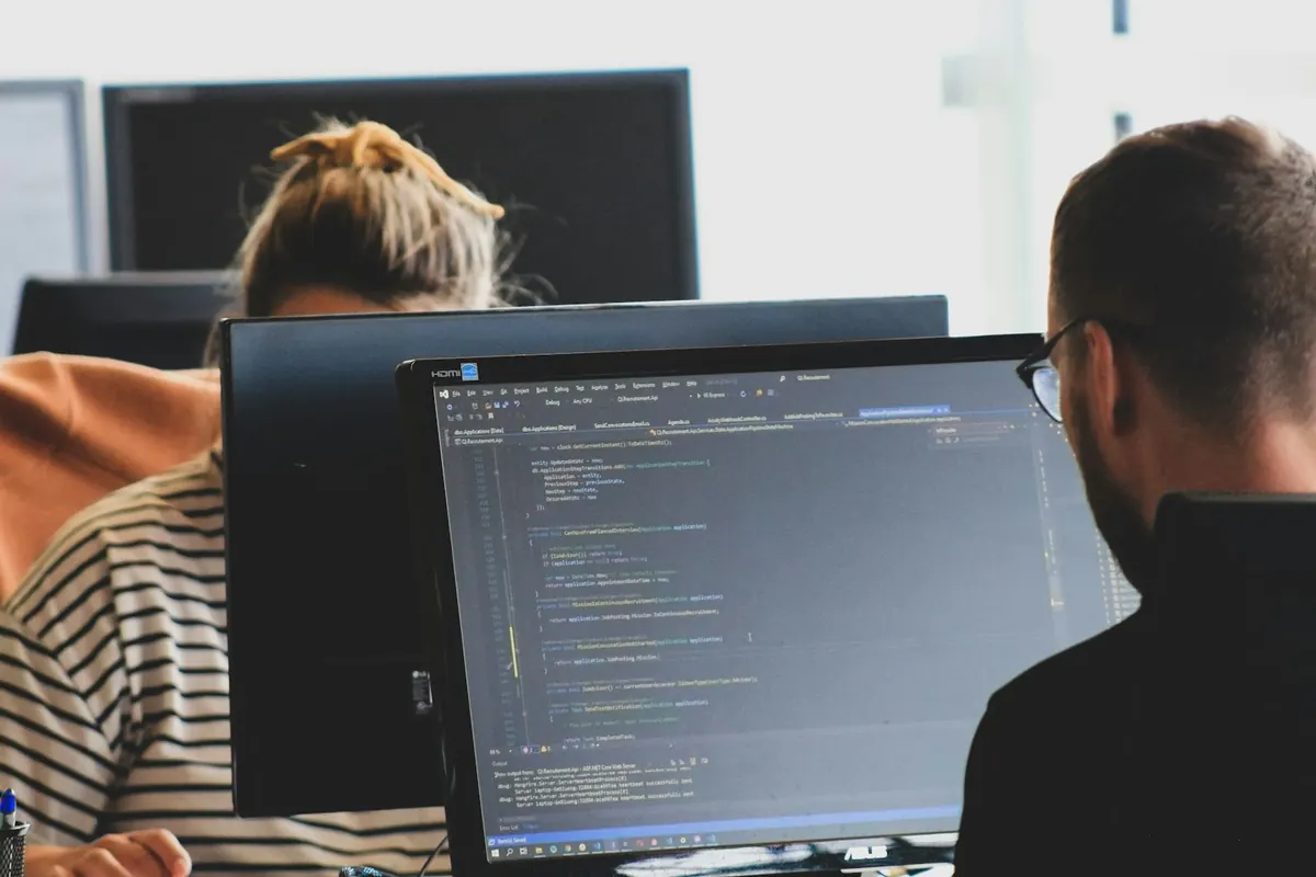 Two engineers working on code at their monitors