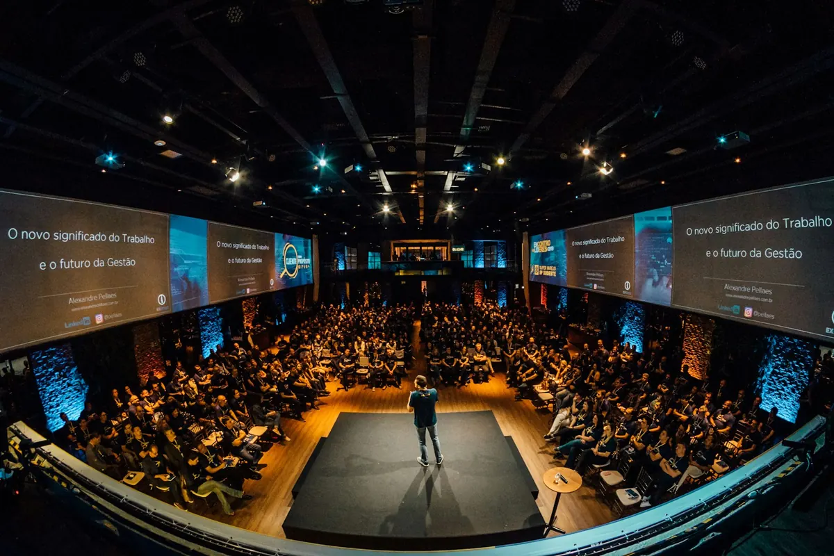 A speaker on a raised stage addressing a large audience
